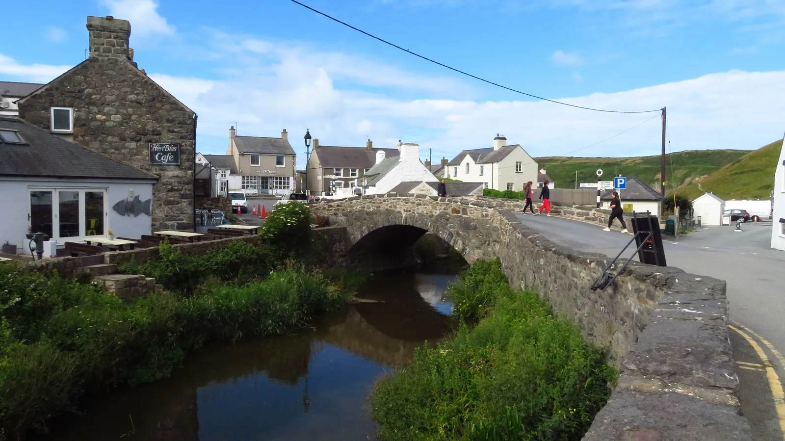 The old stone bridge over the Afon Daron in the middle of Aberdaron, houses and the village street rising behind it