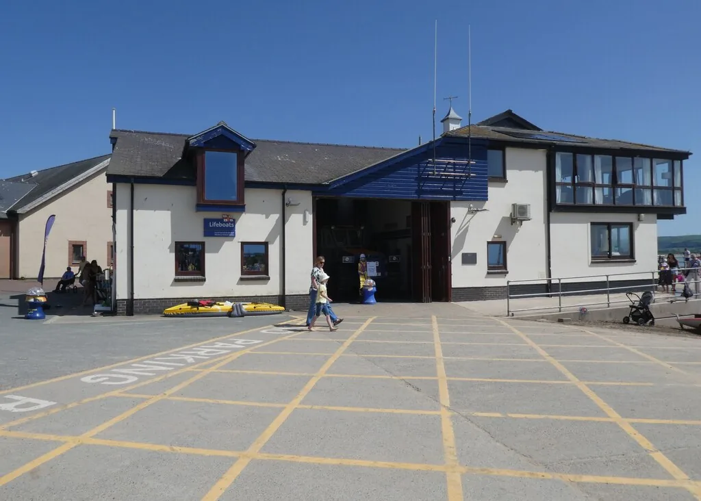 The Aberdyfi lifeboat station beside the wharf, its boathouse doors open and people walking past