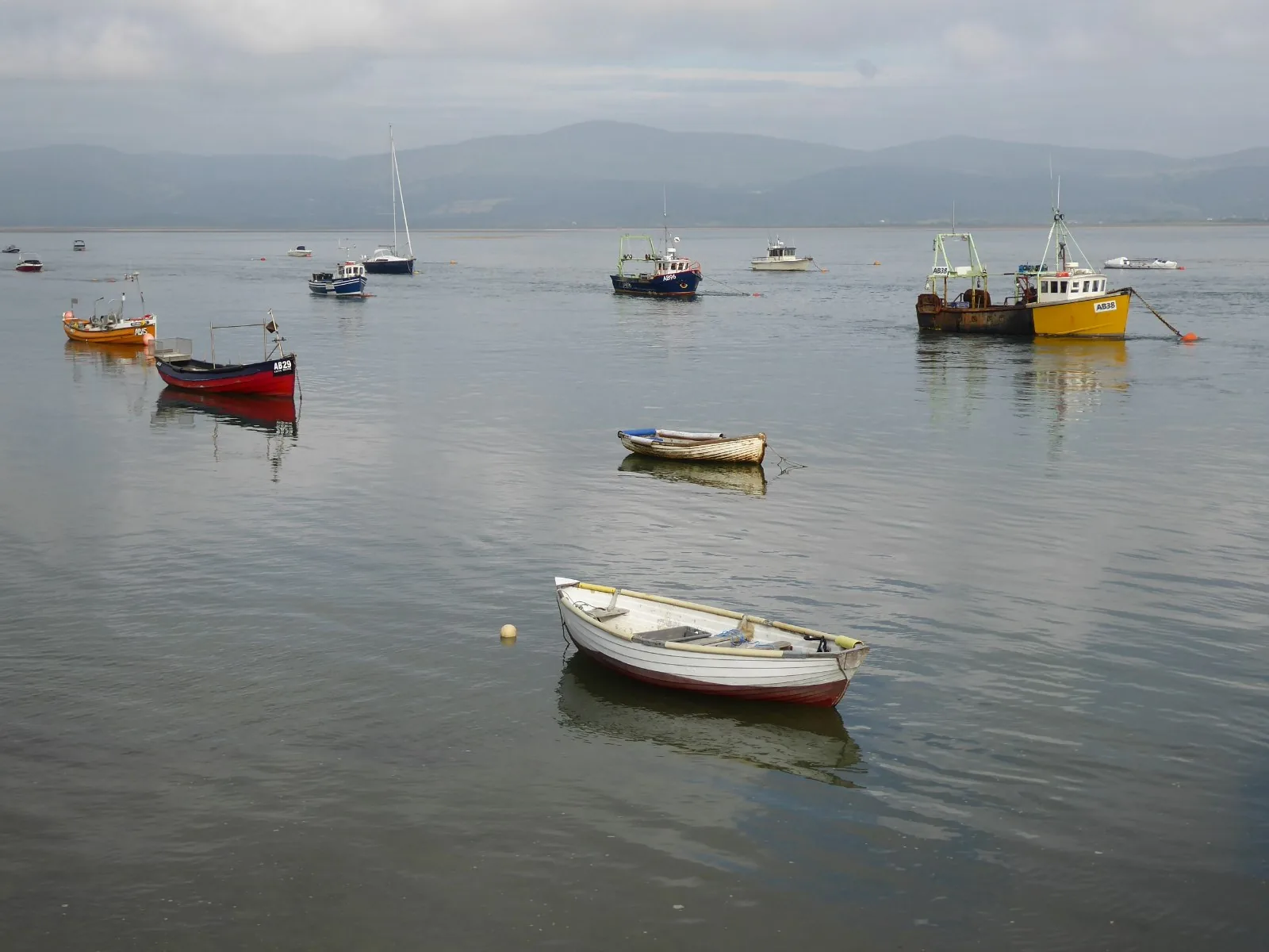 Small fishing boats and dinghies moored on the Dyfi estuary at Aberdyfi, hills fading behind them