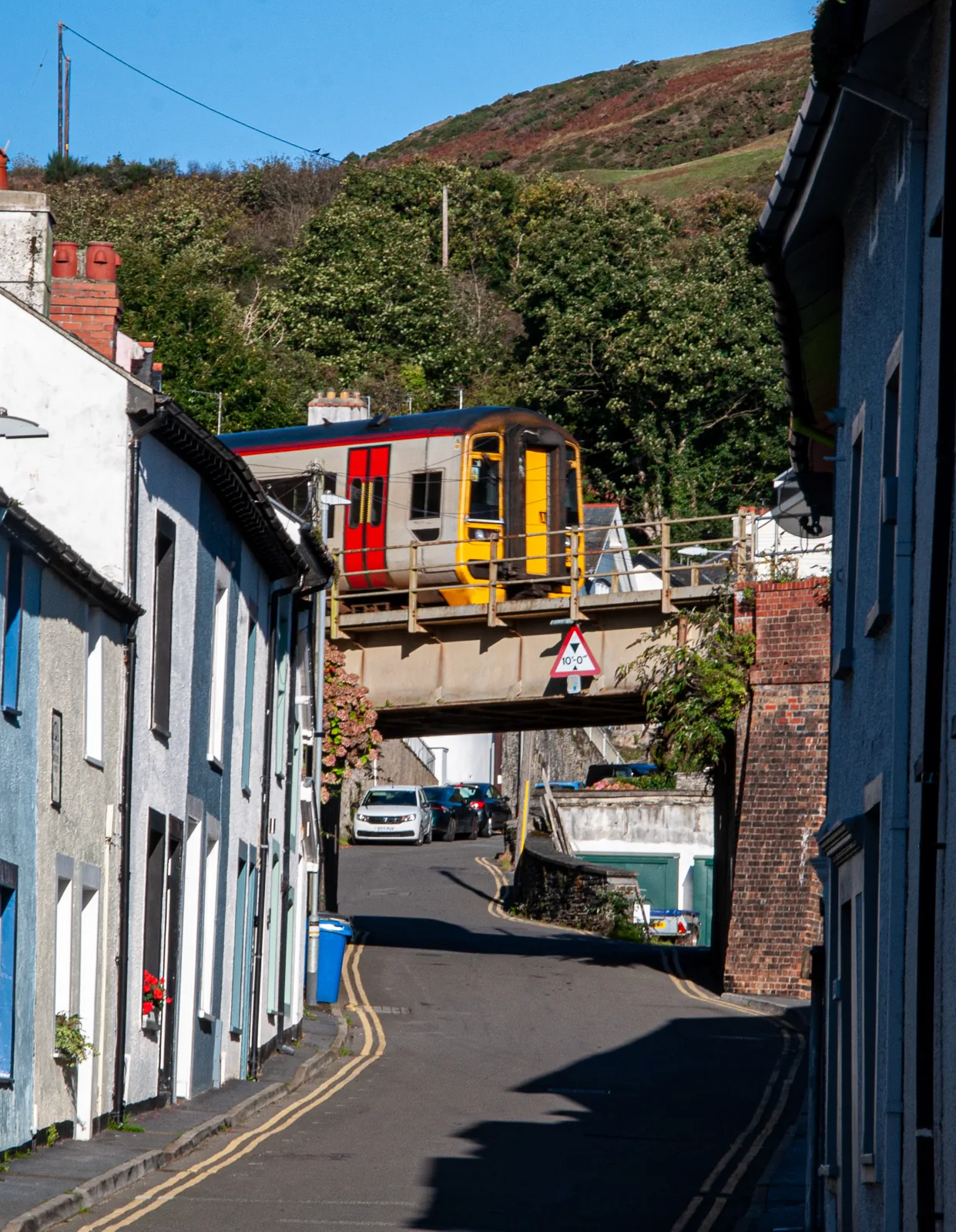 A narrow back street in Aberdyfi with terraced cottages, a train crossing the railway bridge above it