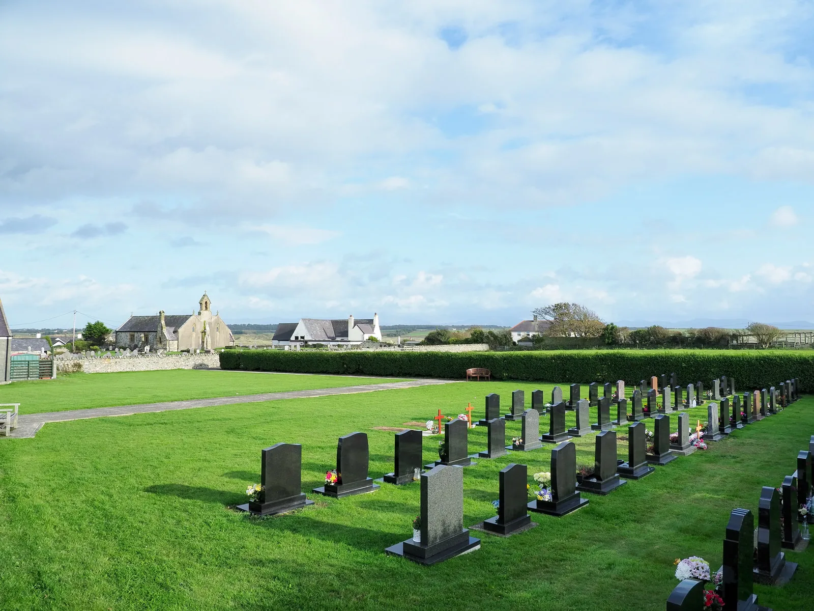 The cemetery at Aberffraw, rows of headstones on open grass with the coast beyond