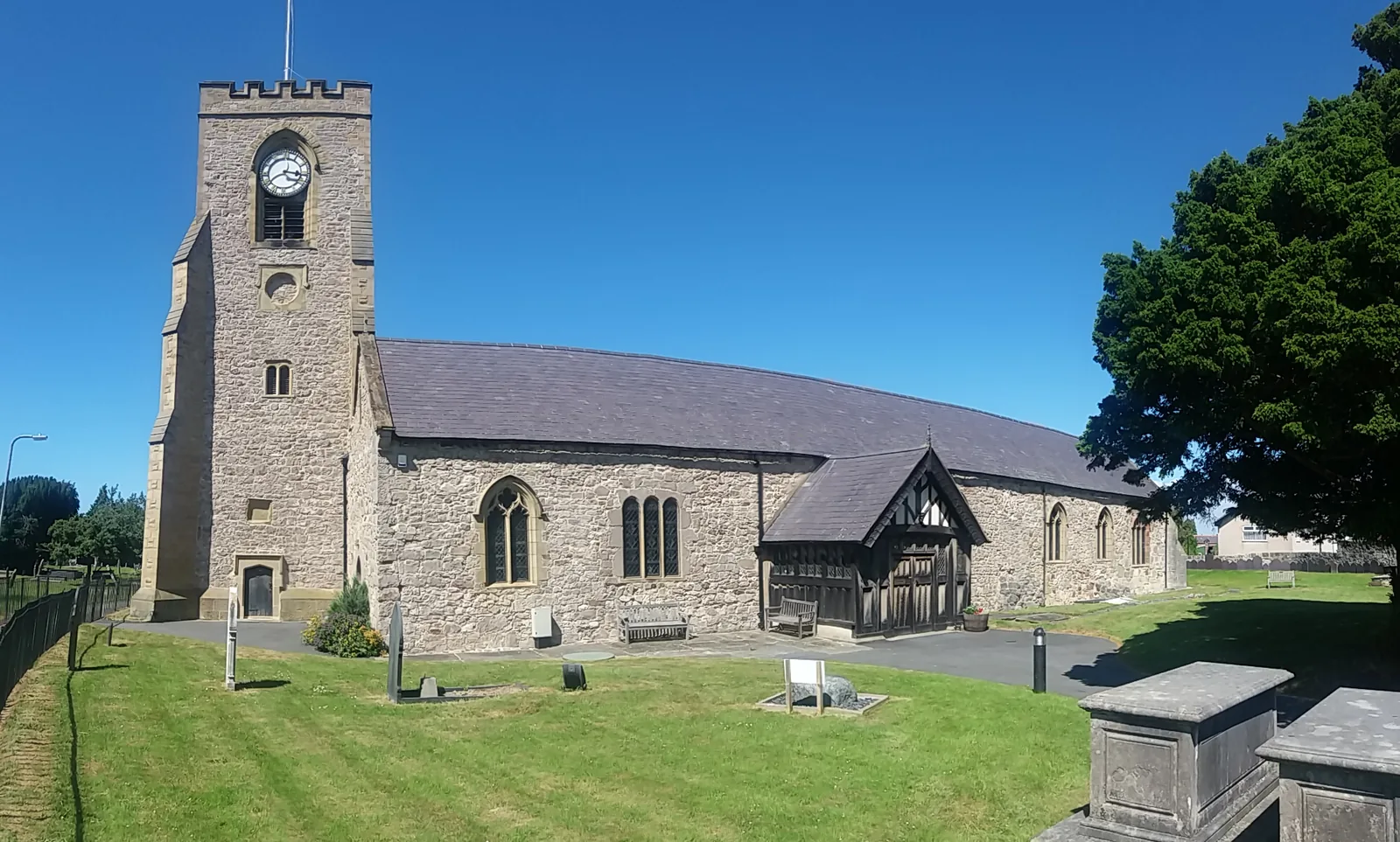 St Michael&rsquo;s Church, Abergele, its low twin-naved body and battlemented west tower seen across the churchyard grass