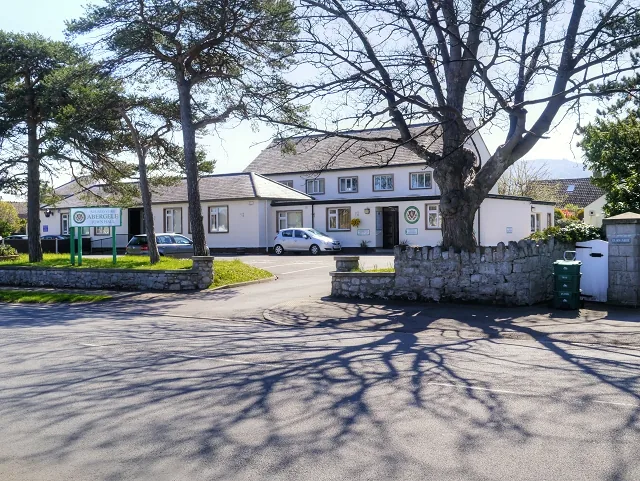 Abergele Town Hall, a low white building behind a stone wall and a large bare tree
