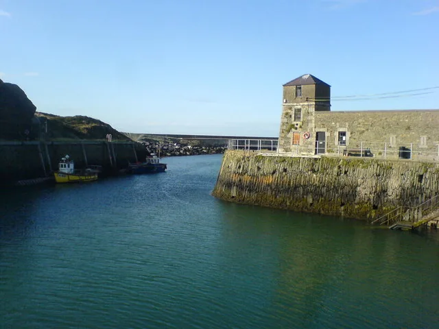 The narrow inlet of Amlwch Harbour, the Watch House standing on the walled quay above green water
