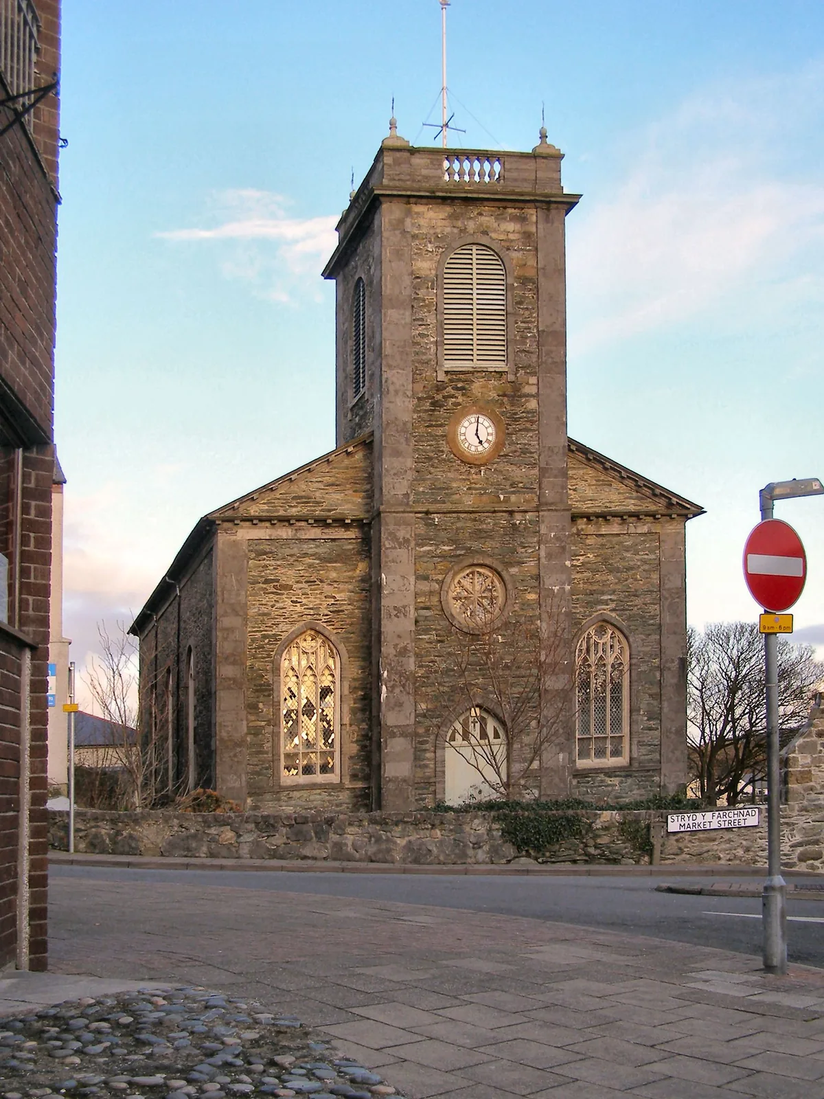 St Eleth's Church, Amlwch, its clock tower lit by low sun beside the bilingual Stryd y Farchnad / Market Street sign