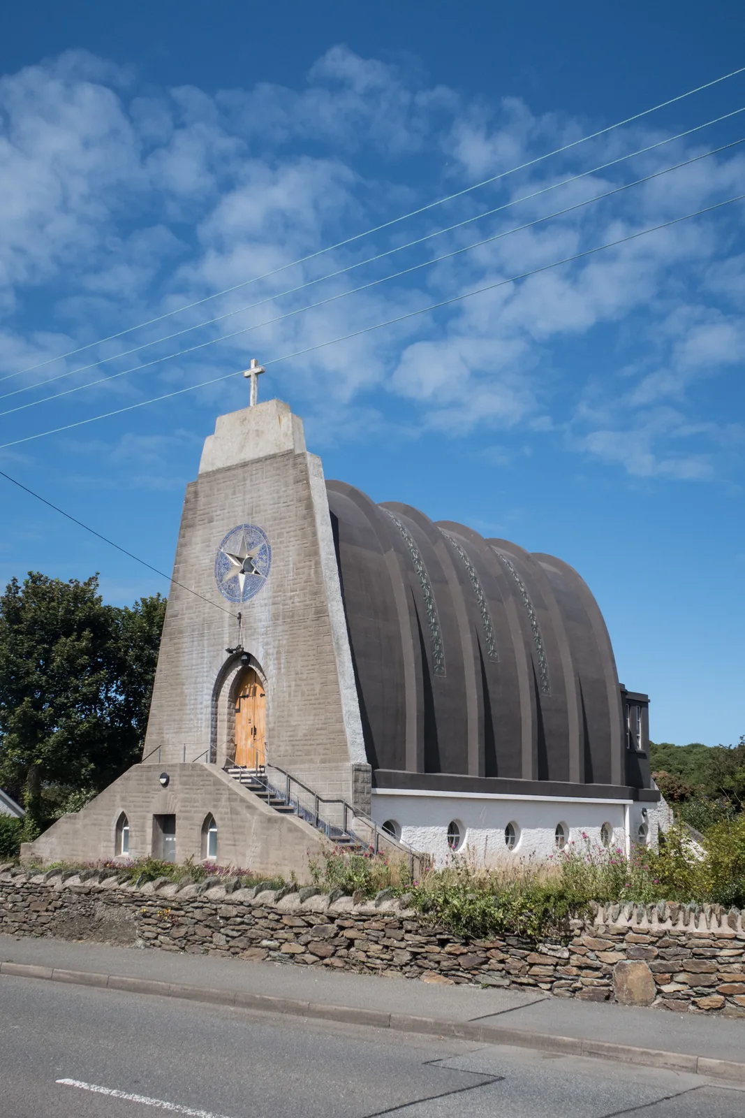 Our Lady Star of the Sea and St Winefride, Amlwch: the concrete parabolic ribs of the roof and the star window in the tower, under a blue sky