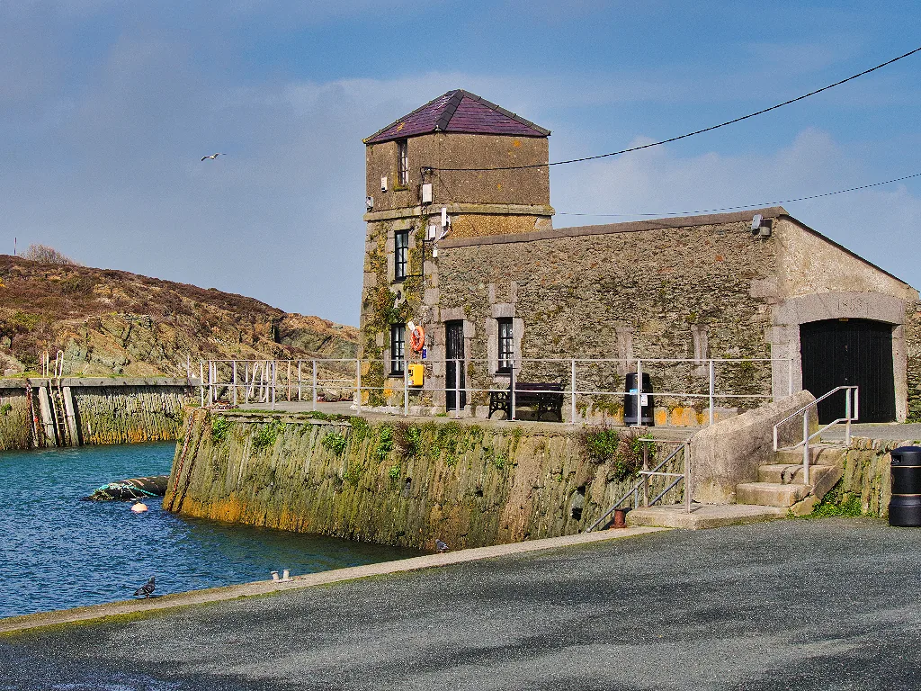 The Watch House on the west quay at Porth Amlwch, its square tower above the harbour wall on a clear day