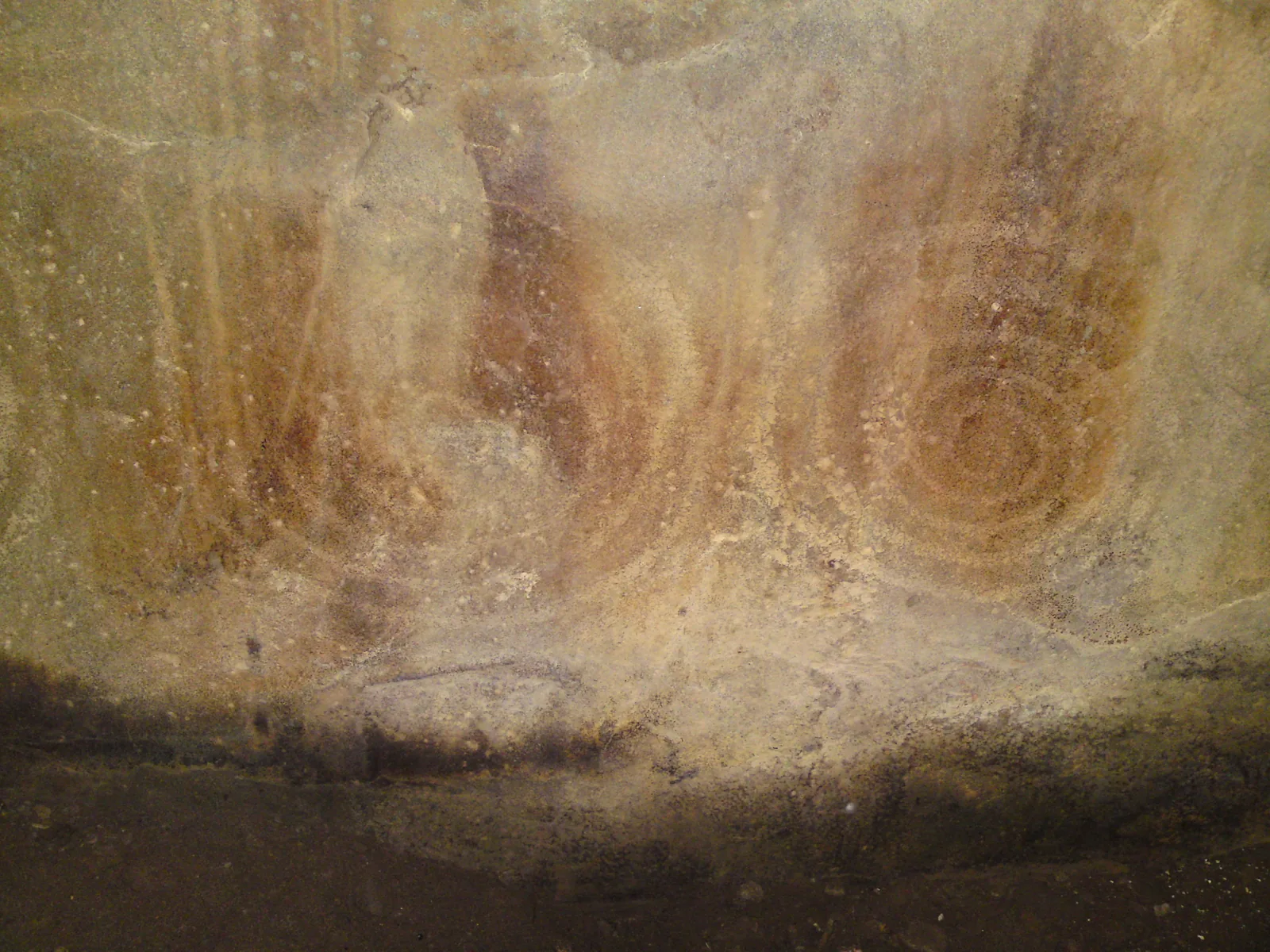 Faint paired concentric spirals pecked into the surface of a stone inside the chamber at Barclodiad y Gawres.