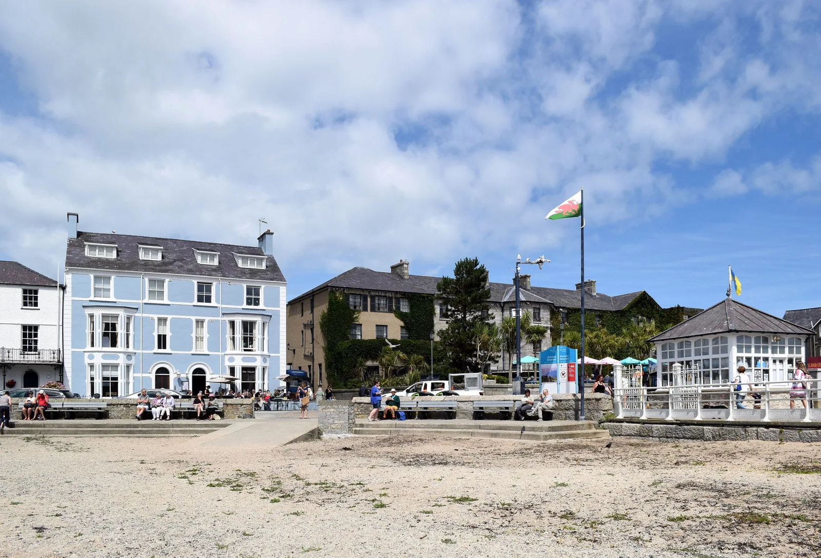 The seafront and Green at Beaumaris, Georgian townhouses behind benches and a flagpole flying the Welsh flag