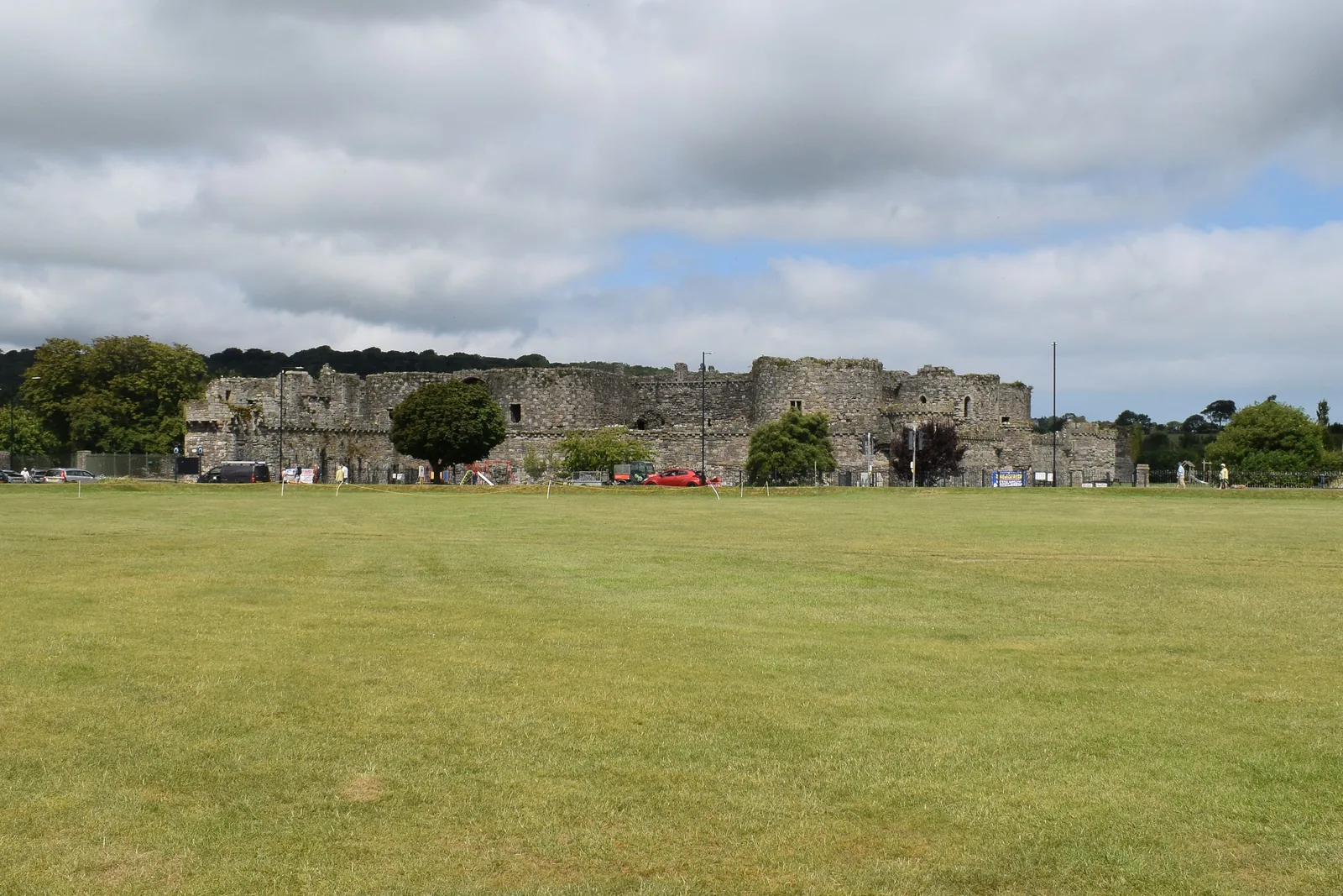 Beaumaris Castle's ruined outer walls seen across The Green, the town's grass common in the foreground