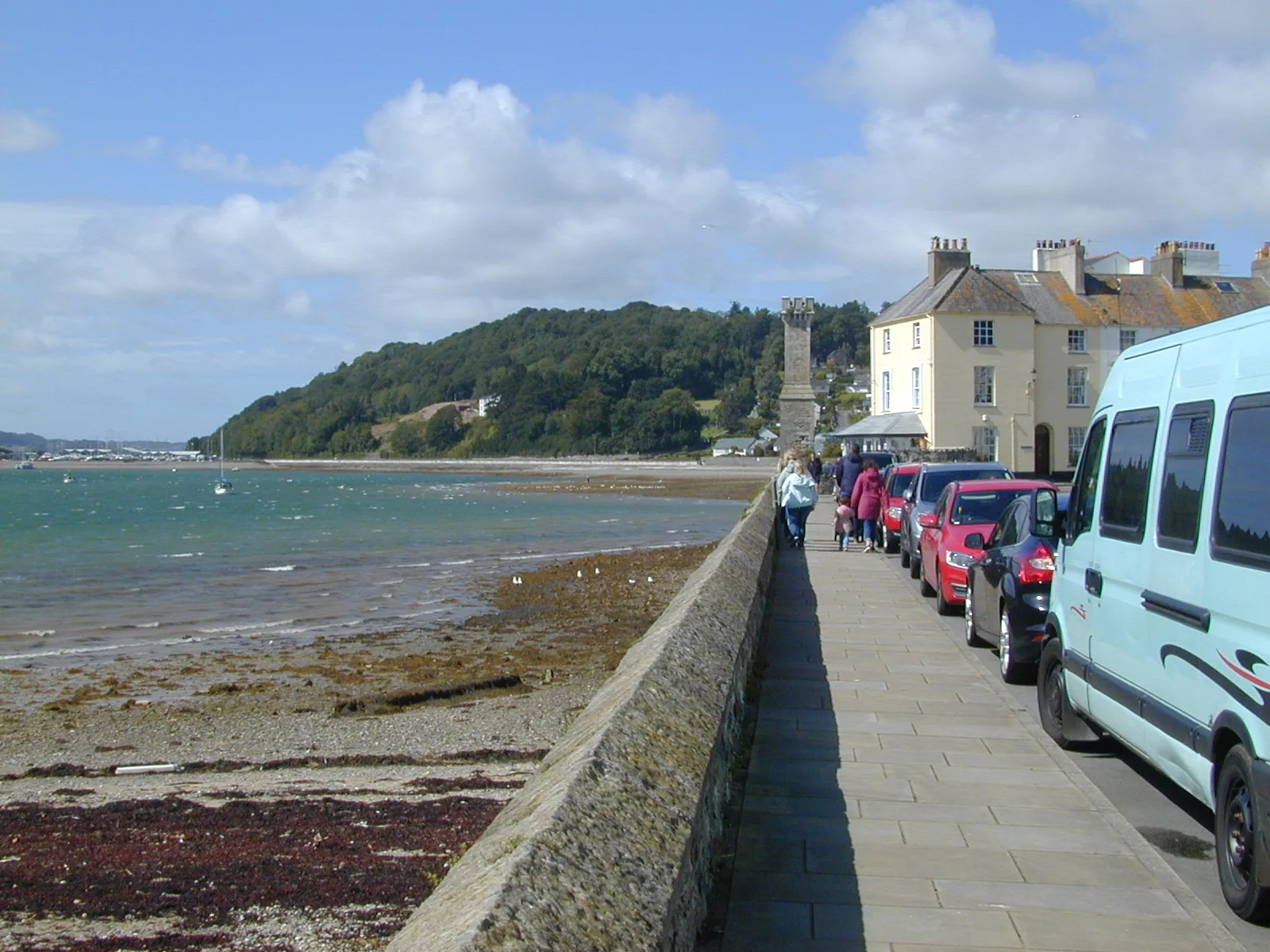 The promenade along Beaumaris seafront at low tide, parked cars and townhouses along the front