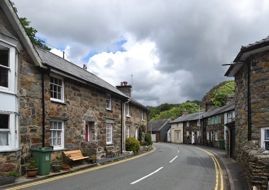 The daytime village street of Beddgelert, stone cottages beneath the hills of Eryri.