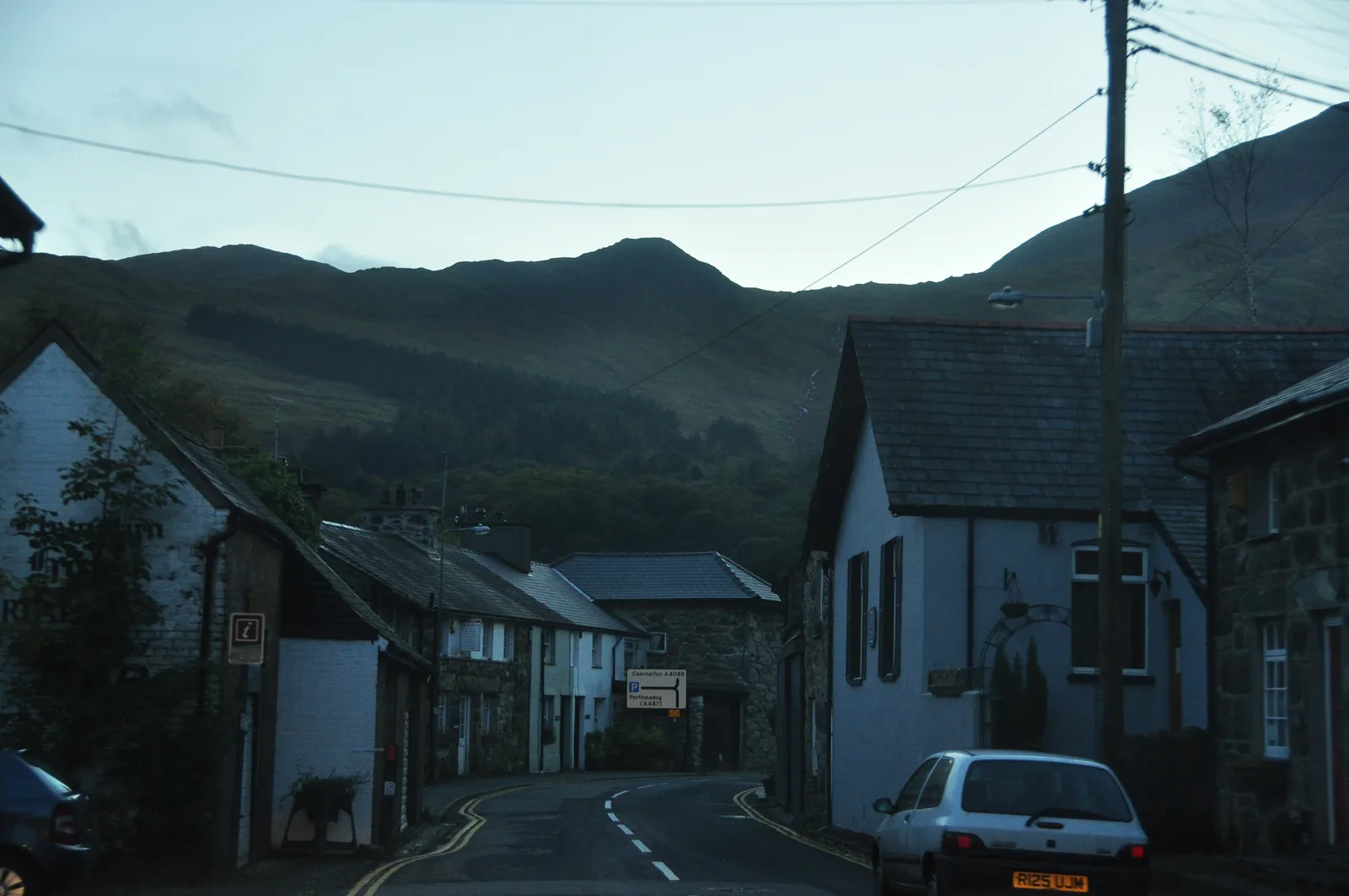 A quiet street in Beddgelert at dusk, stone terraces beneath the hills