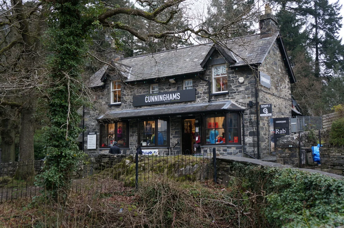 A lit outdoor-equipment shopfront in a stone building in Betws-y-Coed