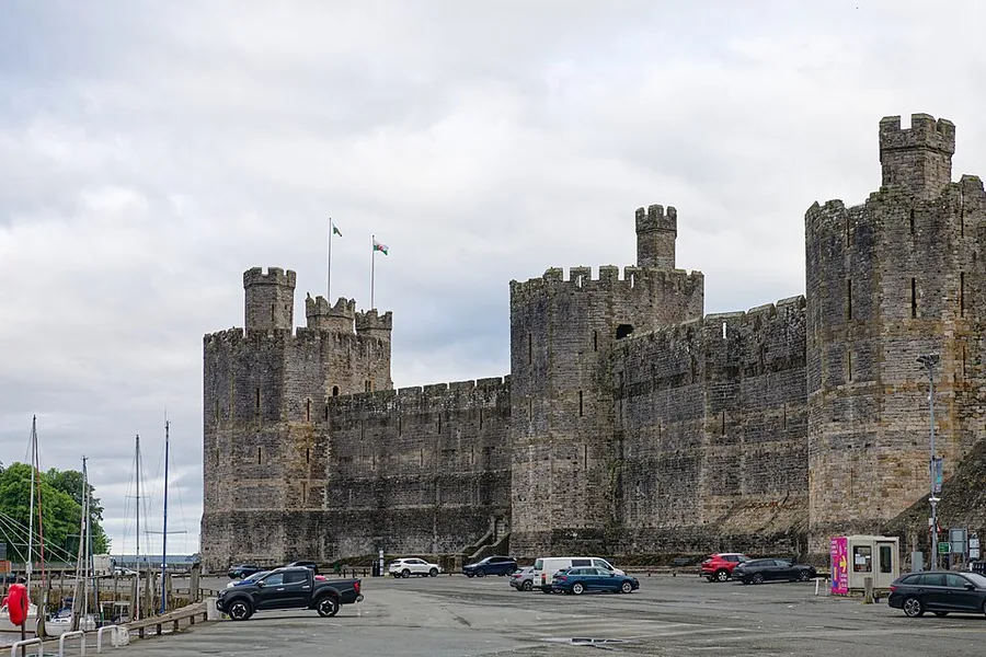 The polygonal banded towers and curtain walls of Caernarfon Castle above the harbour, Gwynedd.