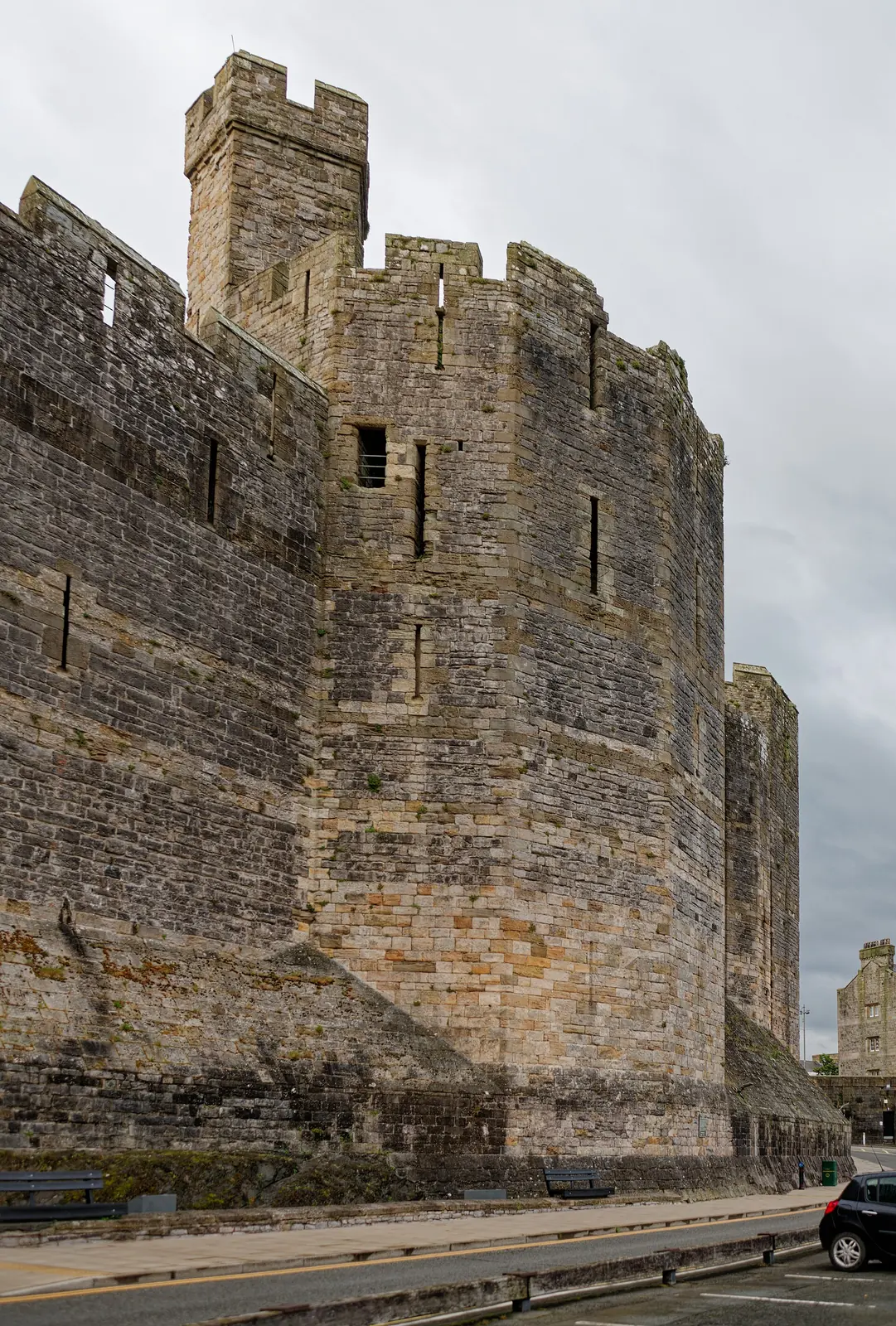The Black Tower at Caernarfon Castle, its crenellated turret rising against a grey Gwynedd sky above the town walls.