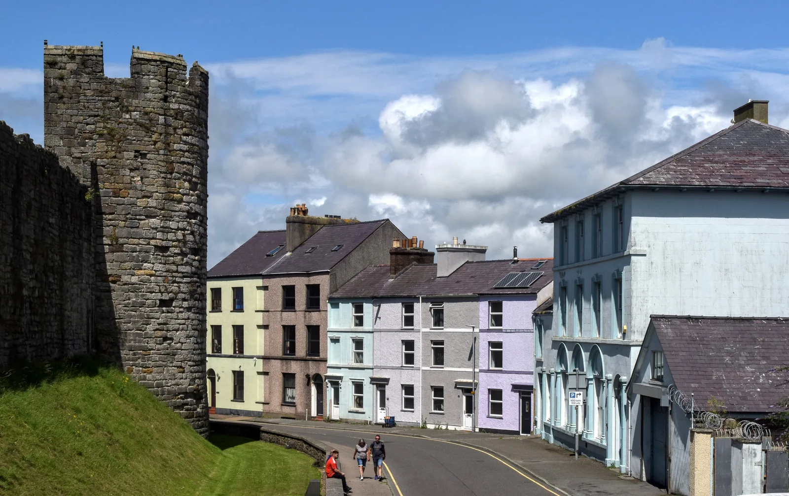 A round medieval wall tower on Bank Quay, Caernarfon, with a row of pastel-painted terraced houses running away from it