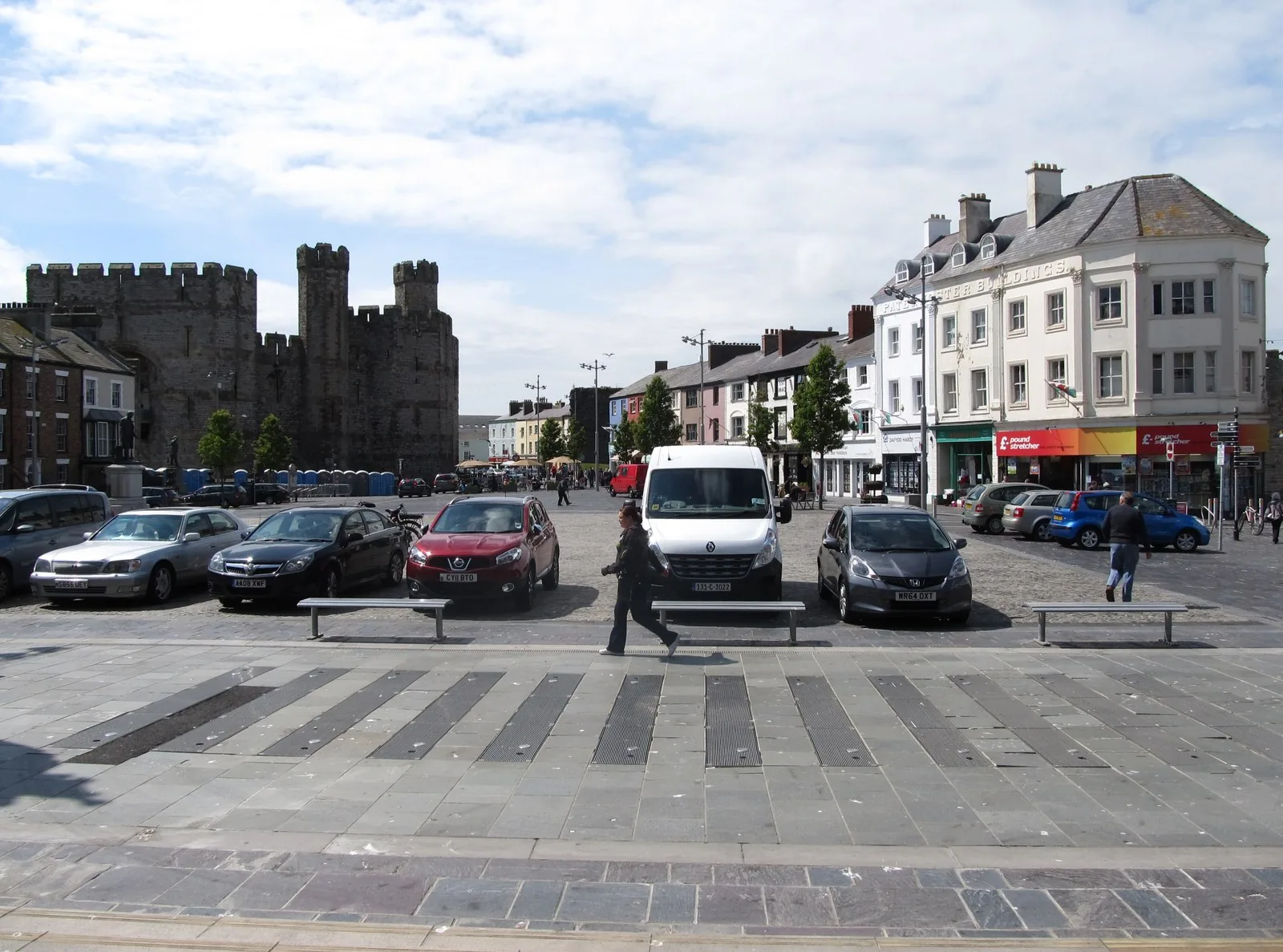 Y Maes, Caernarfon, with benches and paving in the foreground, the castle to the left and a Georgian terrace of shops to the right