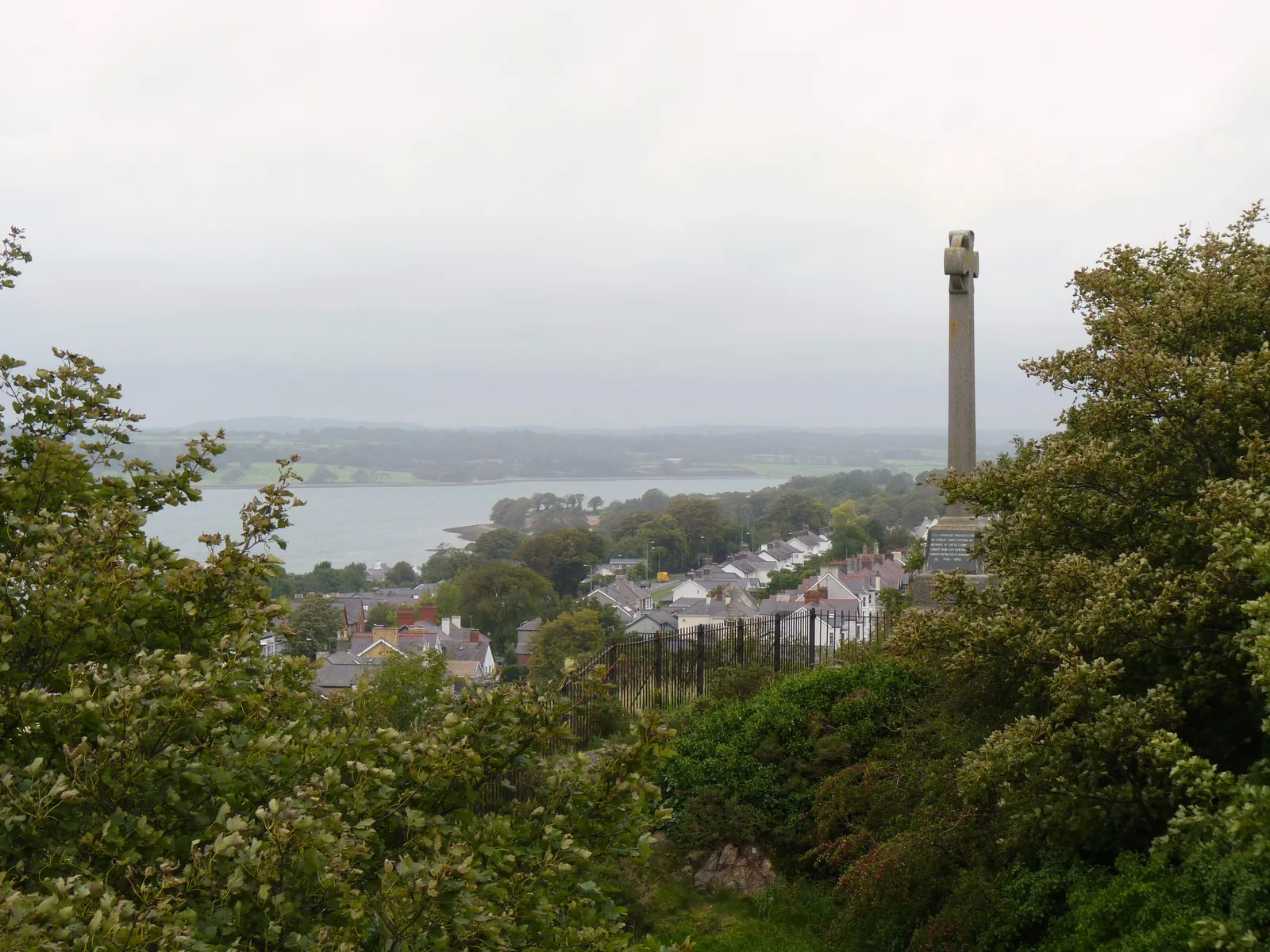 The town roofs and the Menai Strait seen from Twthill, a war memorial column standing above Caernarfon