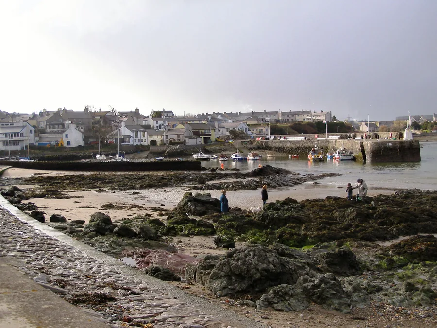 Cemaes Bay, Anglesey: the beach and harbour breakwater with the village behind.