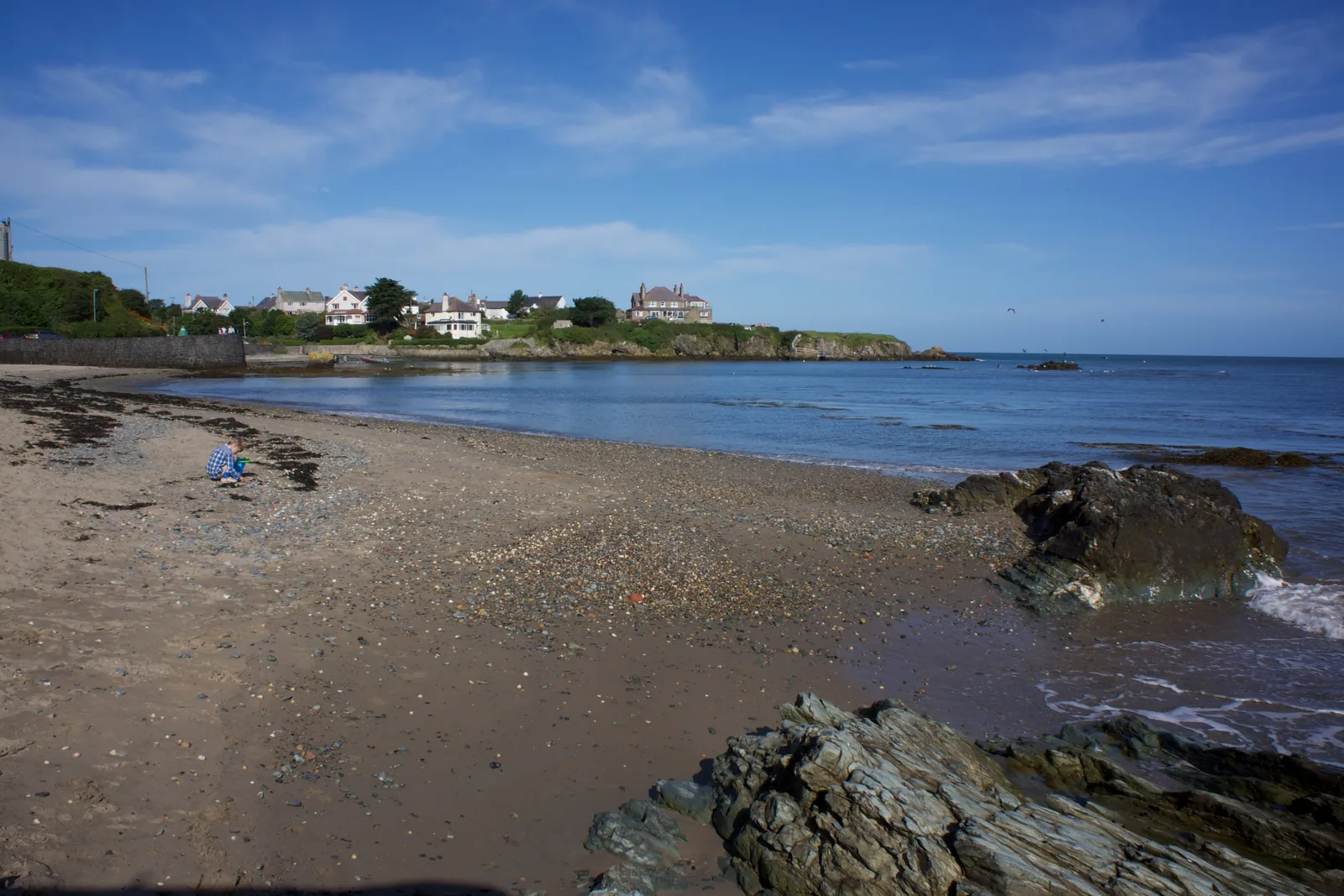 Traeth Bach at Cemaes, a small shingle-and-sand cove with rocks and houses on the low cliff above