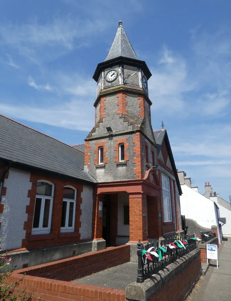 The clock tower of the David Hughes village hall, Cemaes, against a blue sky