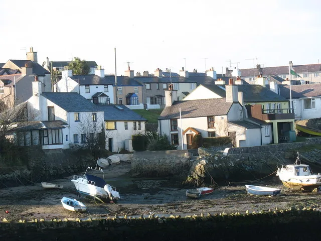 Houses stacked above the harbour at Cemaes, with boats on the sand below