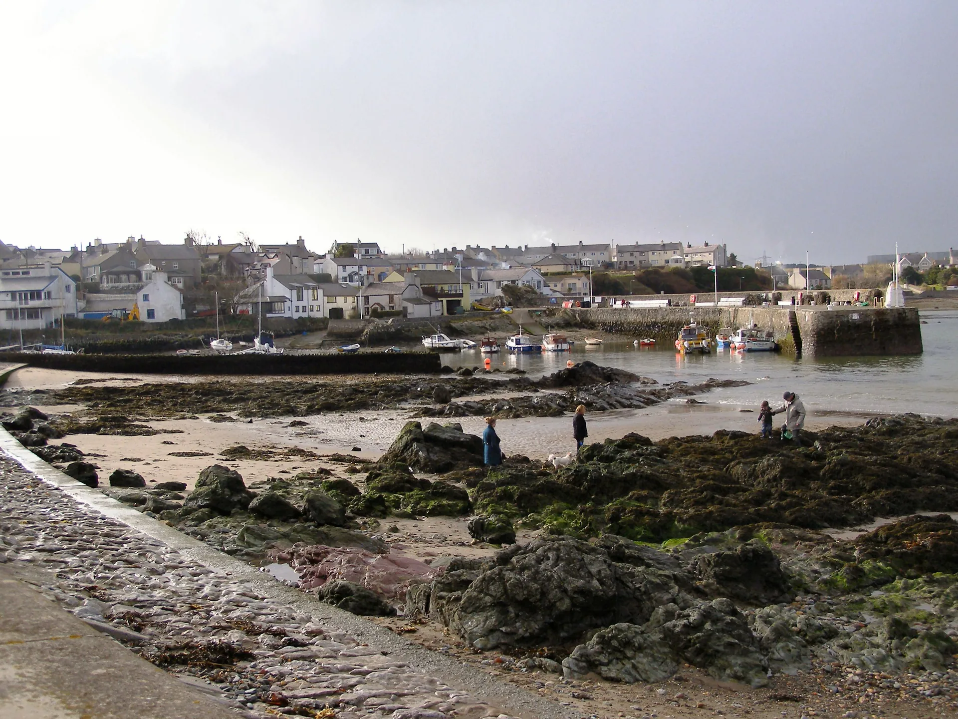 Cemaes Bay, Anglesey: the beach and the harbour breakwater with the village terraces rising behind