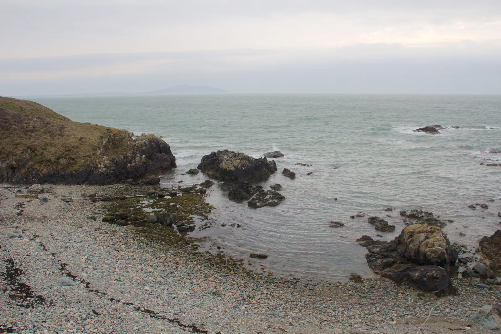 Sand, pebbles and rock along the shoreline at Church Bay at lower tide