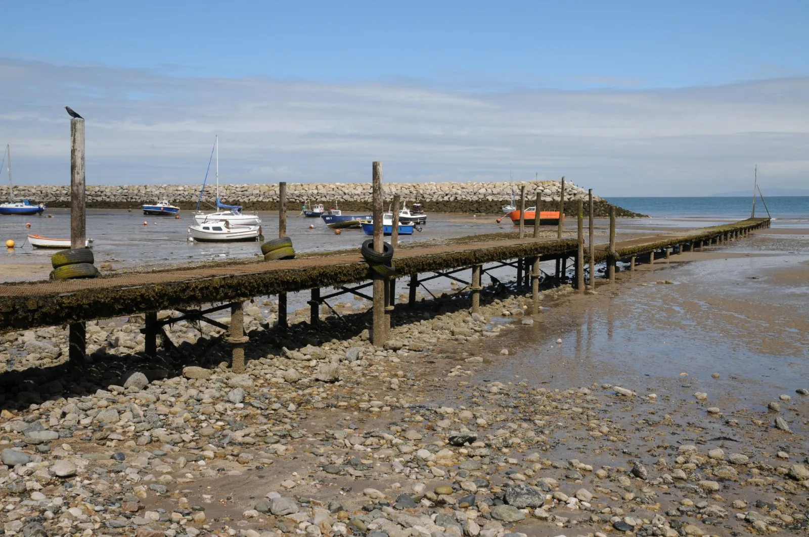 The jetty at Rhos-on-Sea at low water, small boats resting on the sand beside it
