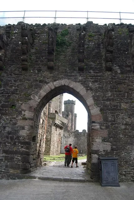 A fortified stone archway at Conwy Castle's west barbican, with a tower visible through the gate.