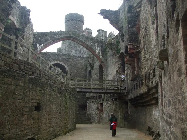 The roofless Great Hall at Conwy Castle, with an intact stone arch and battlement walkway.