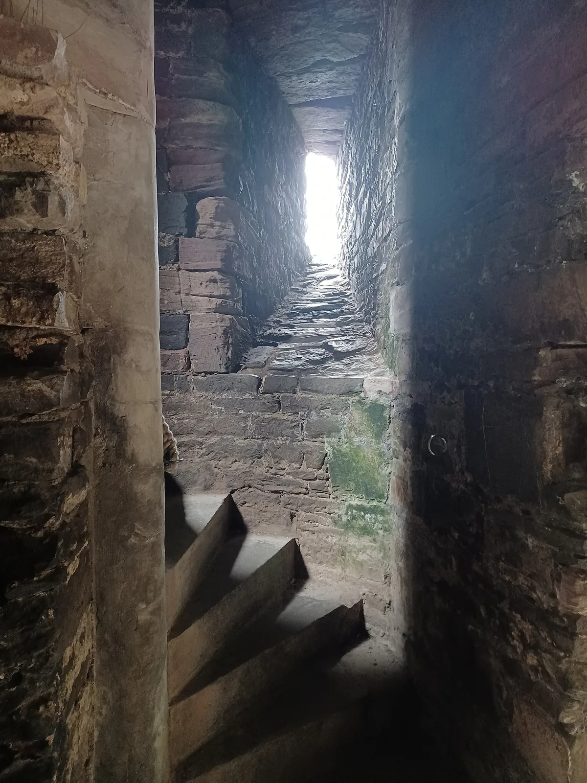A steep, worn stone staircase inside one of Conwy Castle's towers, light at the top.