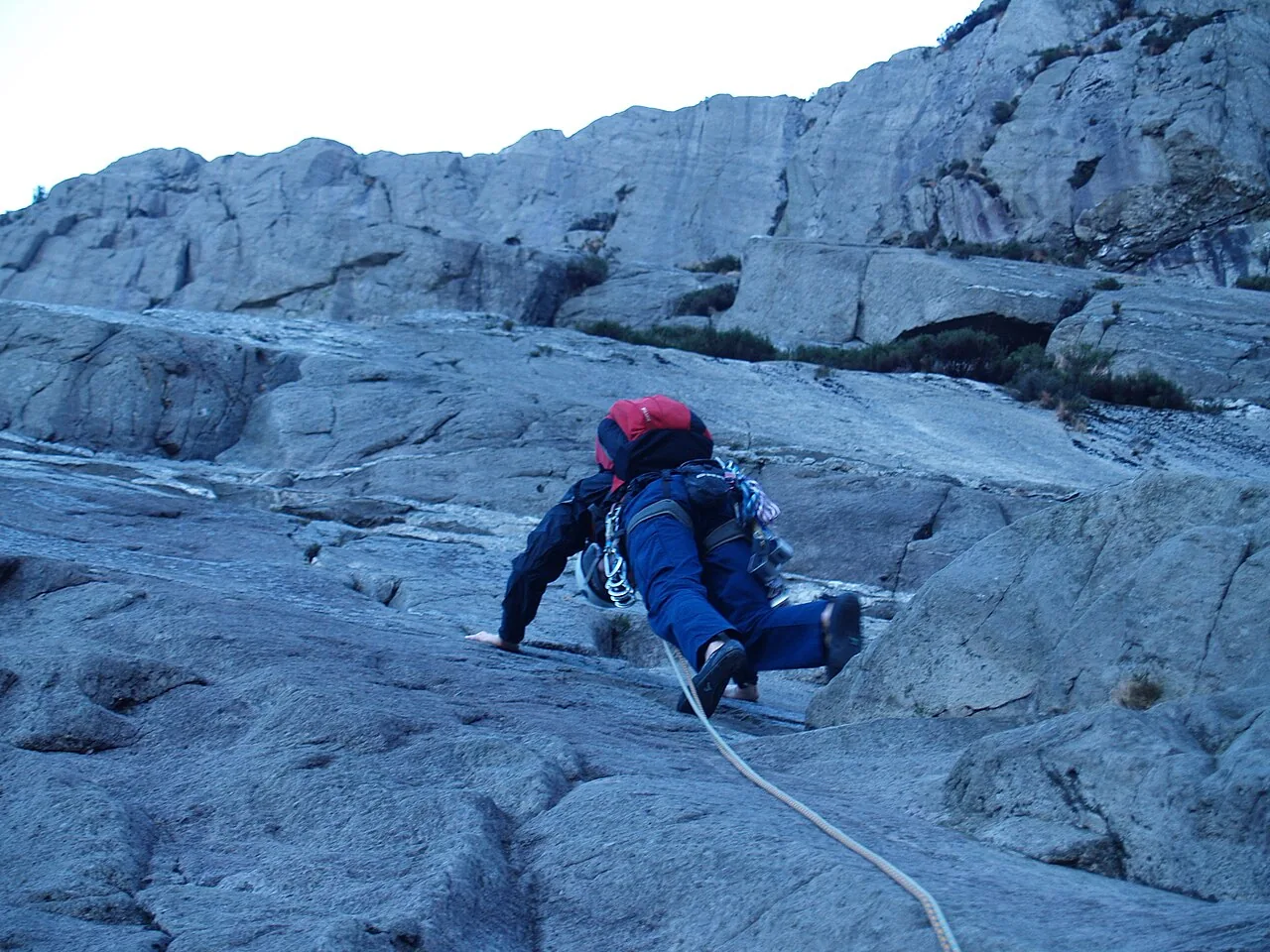 A climber on the pale, sweeping granite of the Idwal Slabs, roped up on the smooth rock.