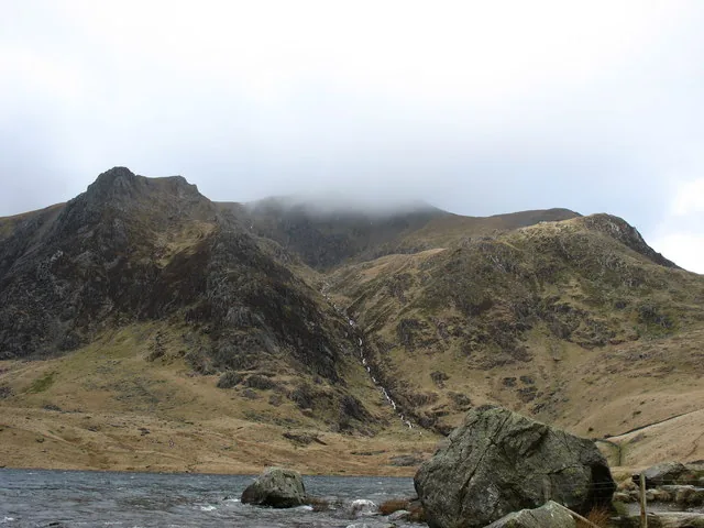 Mist clinging to the western slopes of Cwm Idwal, with a stream channel cutting down through the scree toward the lake.