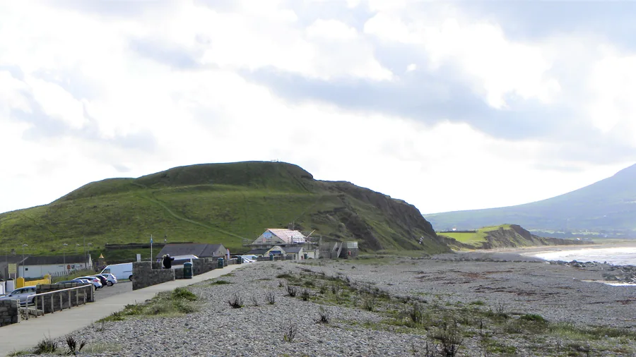 The Iron Age hillfort mound at Dinas Dinlle above its shingle shore, the coast running south towards the hills.