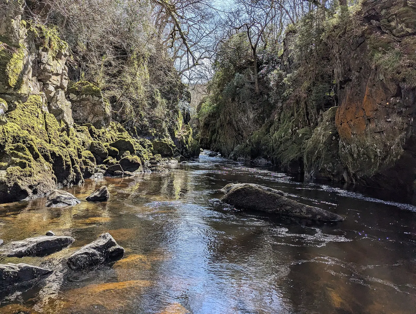 Fast whitewater rapids running through the narrow gorge at Fairy Glen, framed by rock and trees.