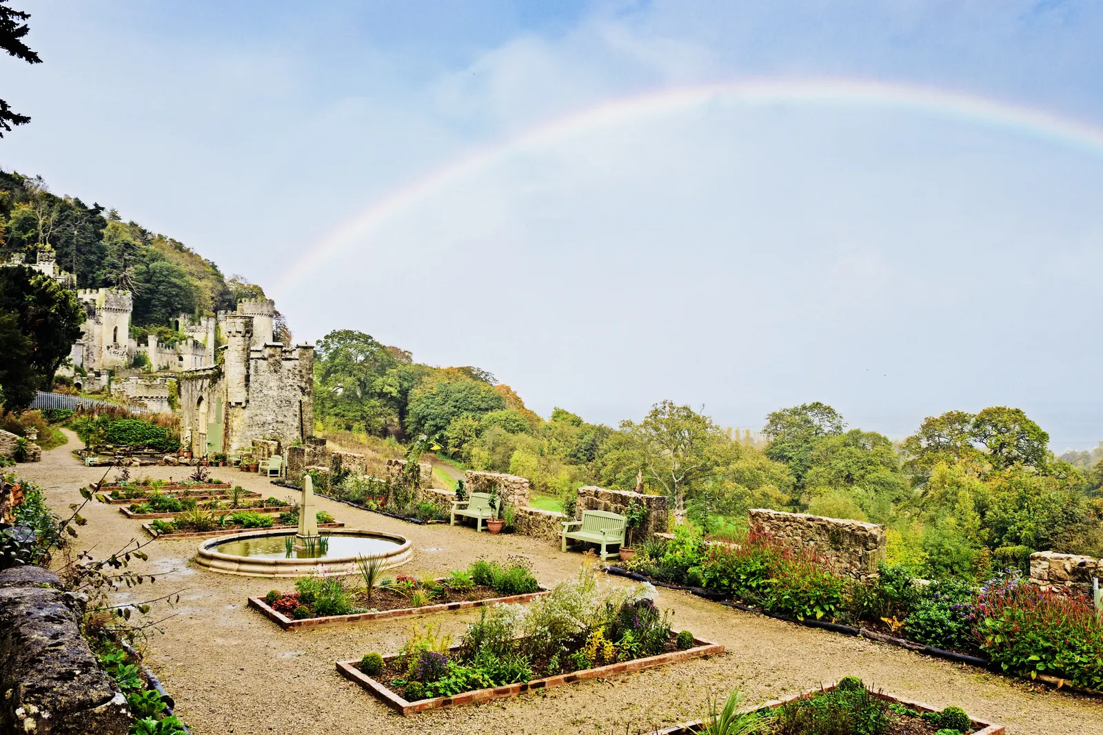 The restored formal garden at Gwrych Castle, with clipped box hedges and a fountain, the castle behind.