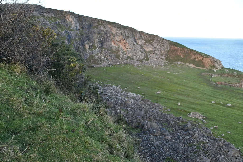 The disused limestone quarry on the Little Orme's Head, its worked rock face above open grassland.