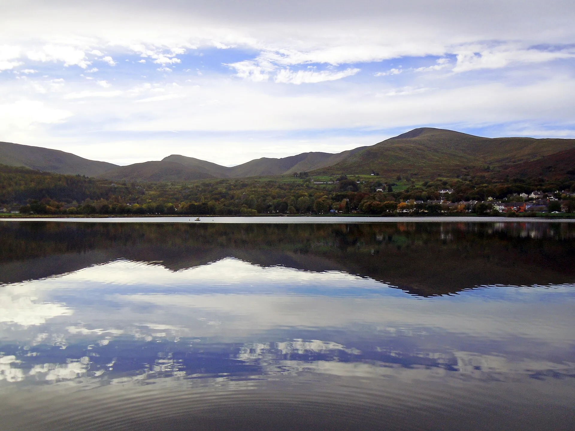 Llyn Padarn's still water reflecting Llanberis village and the mountains of Eryri behind it