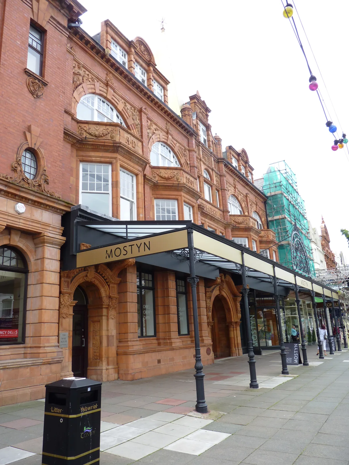 The terracotta and red-brick frontage of MOSTYN on Vaughan Street, Llandudno, the gallery's name across its canopy