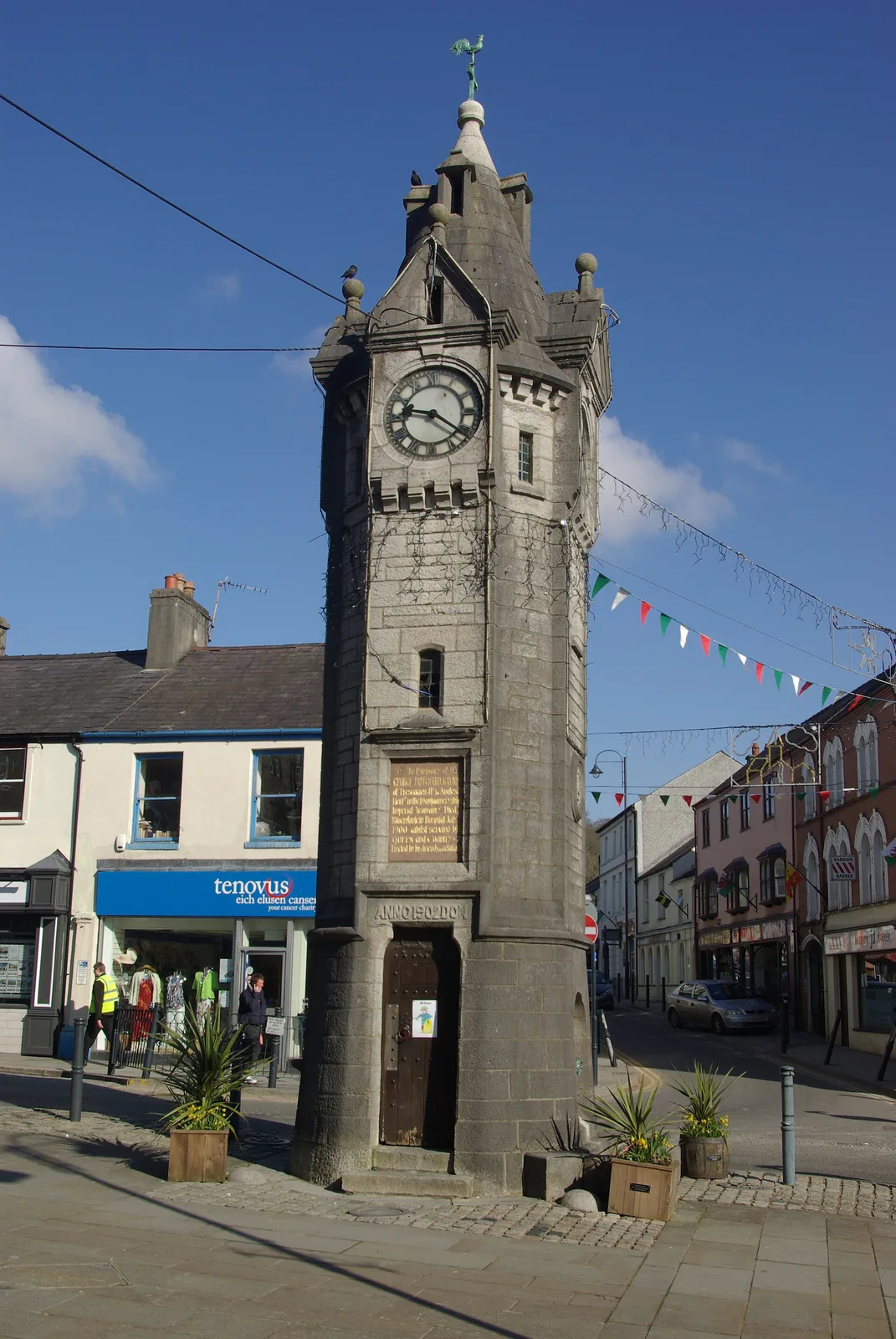 The stone town clock at Llangefni, a tall spired tower with a white clock face and a memorial plaque on its shaft