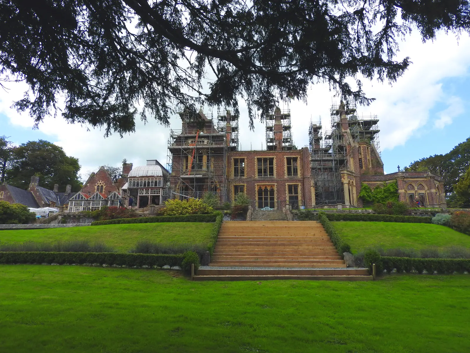 The terraced lawns and stone steps rising to Hafodunos Hall, the scaffolded Gothic front above them