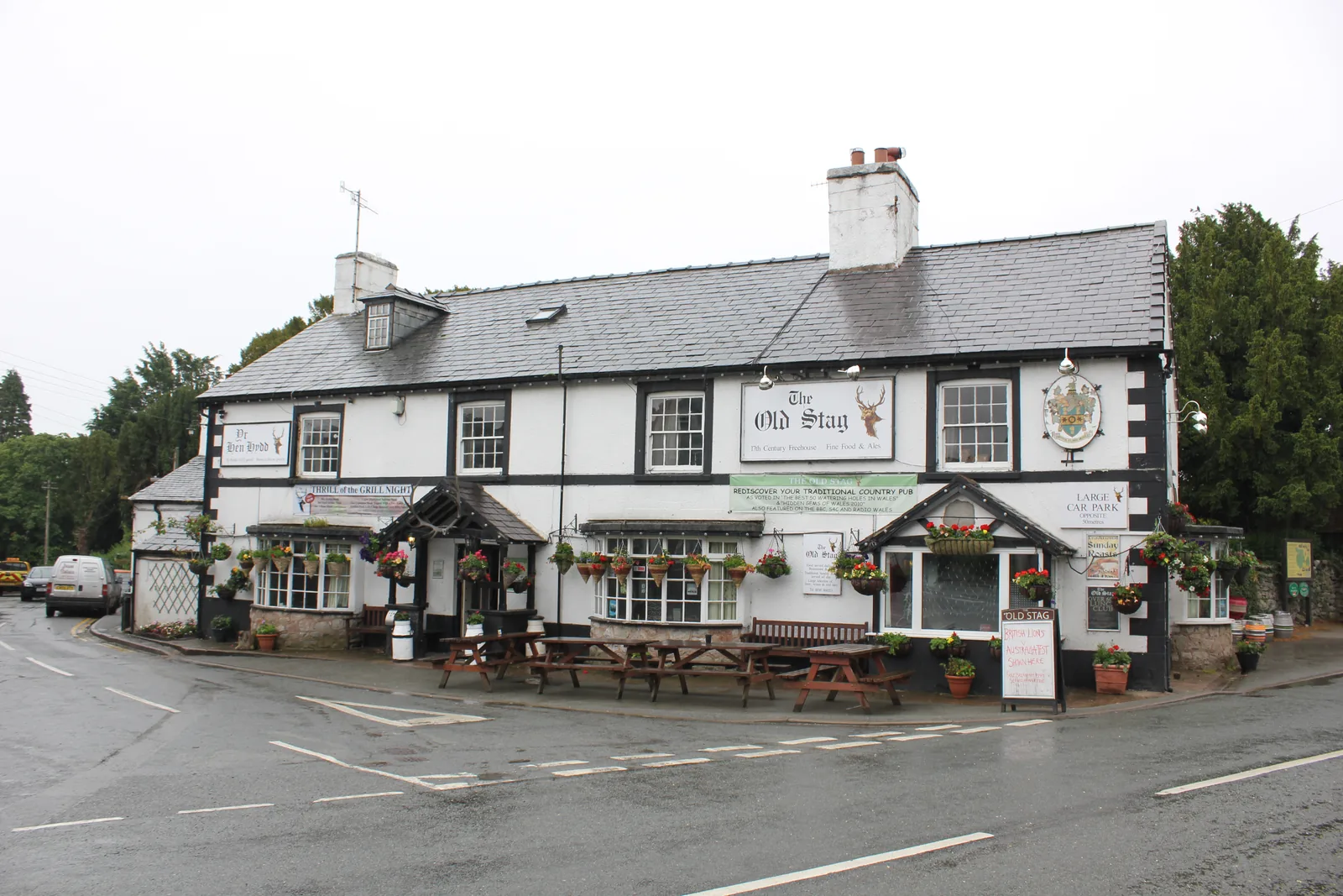The Old Stag at Llangernyw, a long whitewashed frontage with benches along the roadside