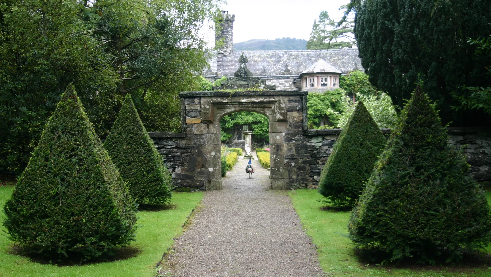 The gardens at Gwydir Castle, clipped hedges and old trees inside walled terraces