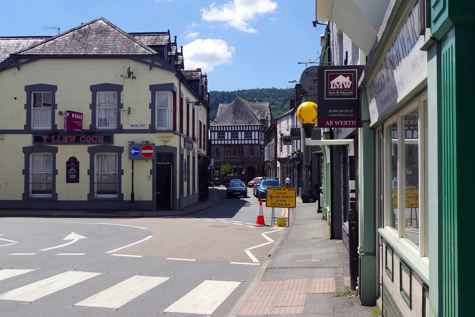 Denbigh Street, Llanrwst: shopfronts and parked cars along the town's main shopping street