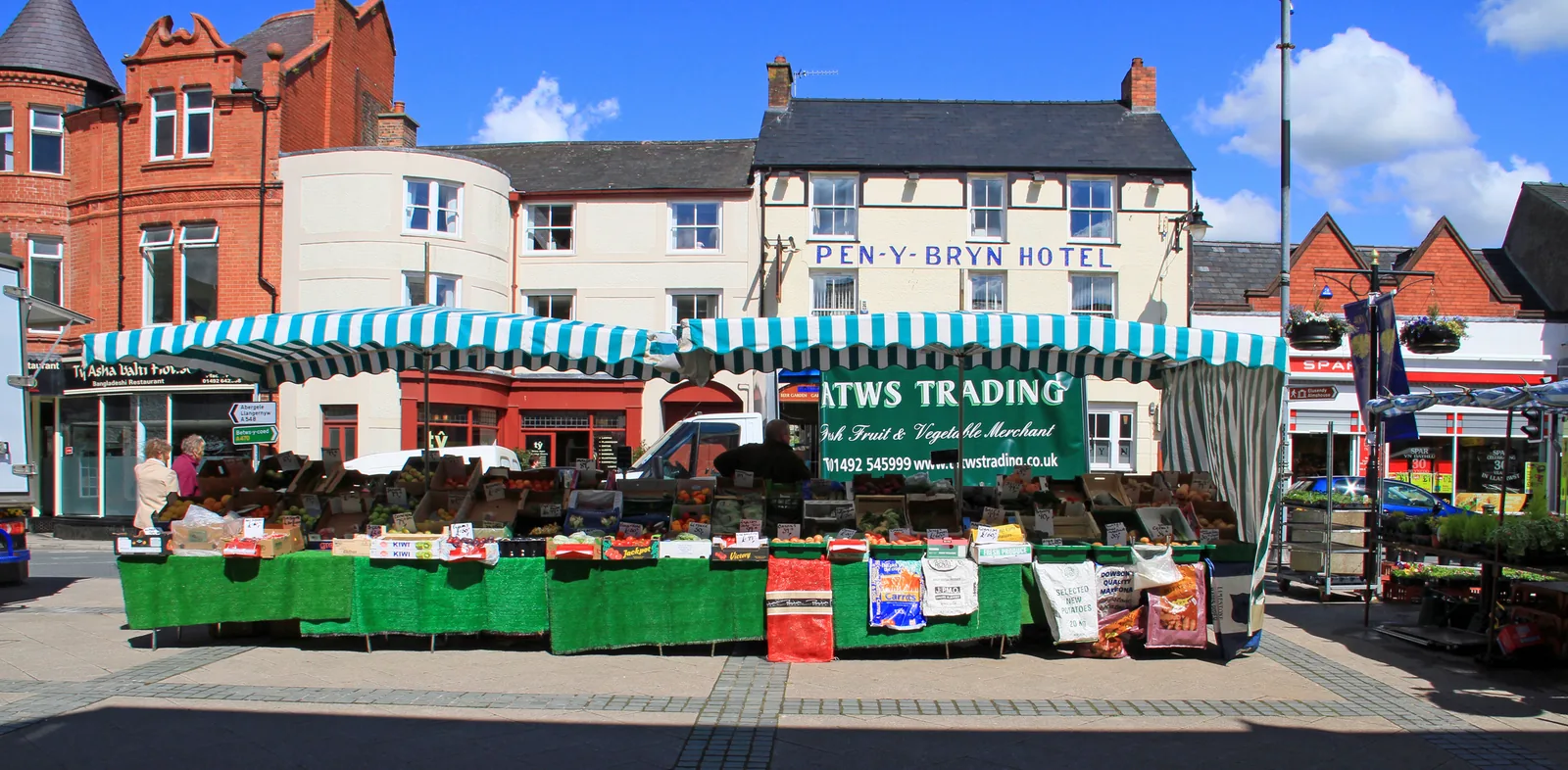 A fruit and vegetable stall trading on the market place at Ancaster Square, Llanrwst, town buildings behind