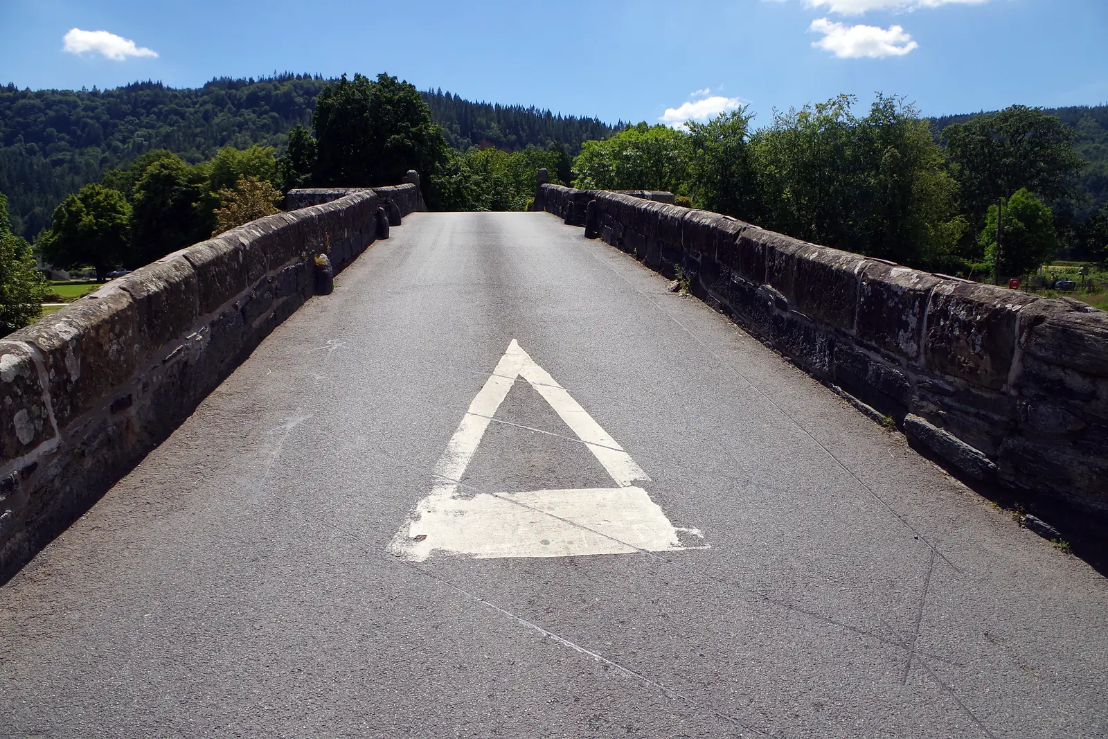 The single-file roadway over Pont Fawr at Llanrwst, rising over the bridge's camber between stone parapets