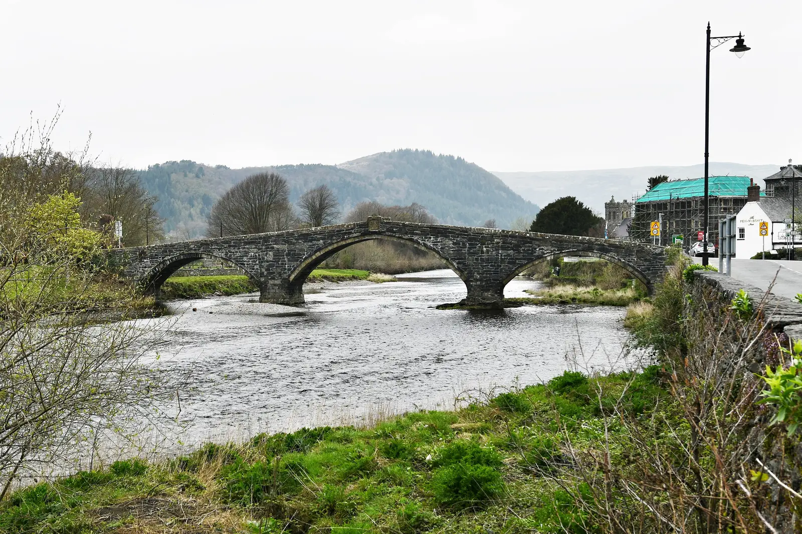 Pont Fawr seen from the riverbank at Llanrwst, its three stone arches carrying the road across the Conwy