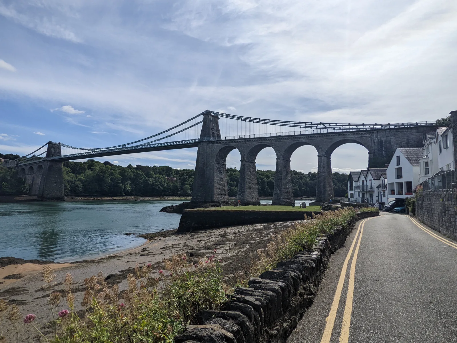 The Menai Suspension Bridge from the Anglesey shore, its full span and stone approach arches carrying the road across the strait